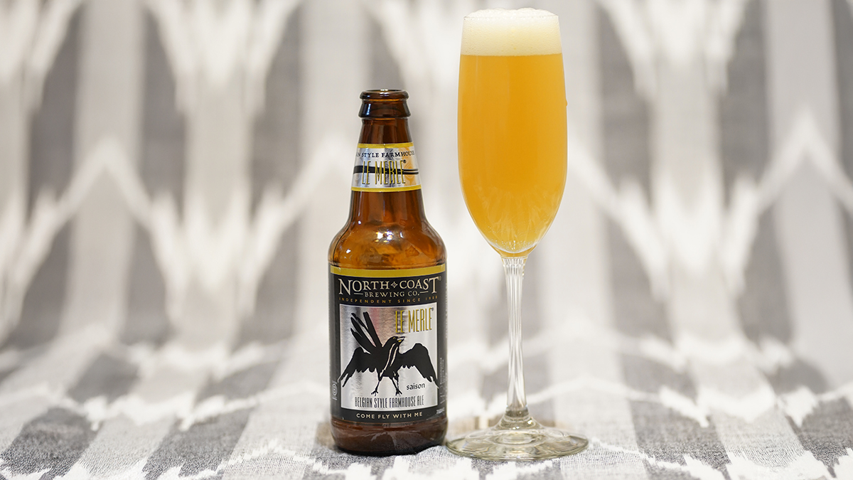A refreshing summer LeMerlemosa in a champagne flute sitting on a table next to a bottle of Le Merle.