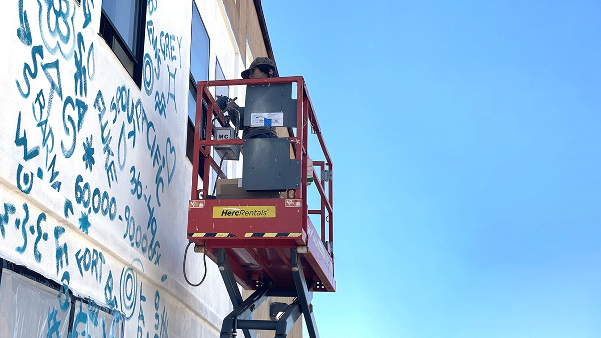 Muralist Marta Alonso Canillar paints the preliminary squiggle grid.