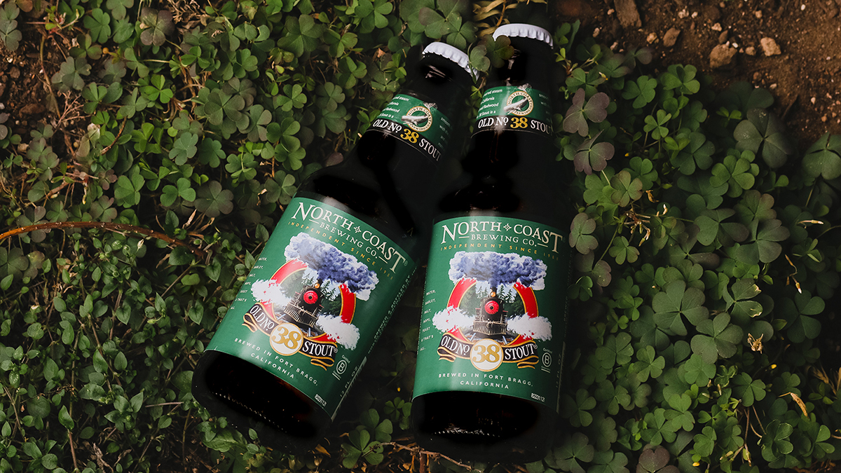 Two bottles of Old No. 38 Stout laying in clover.