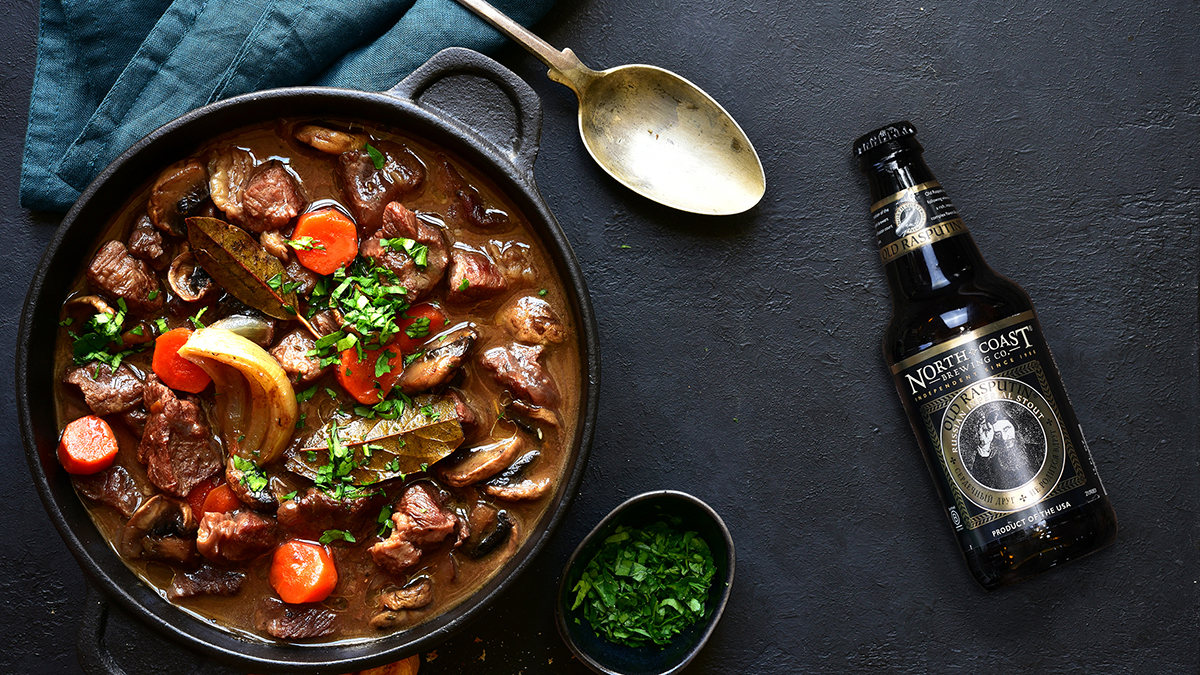 A bottle of Old Rasputin next to a pan of slow-cooked beef stew.