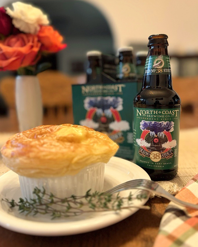 A bottle of Old No. 38 next to a meat pie on a dining room table indoors.