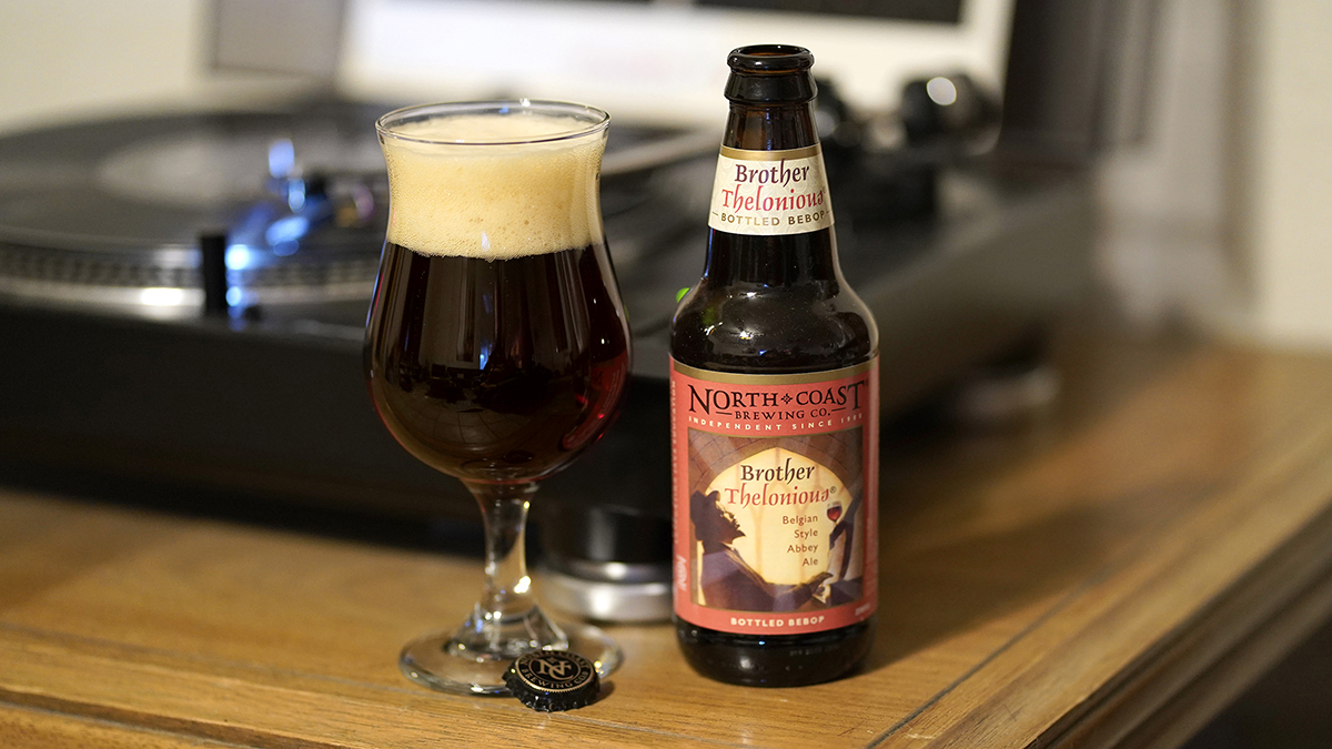 12oz bottle and glass of Brother Thelonious in front of a record player.
