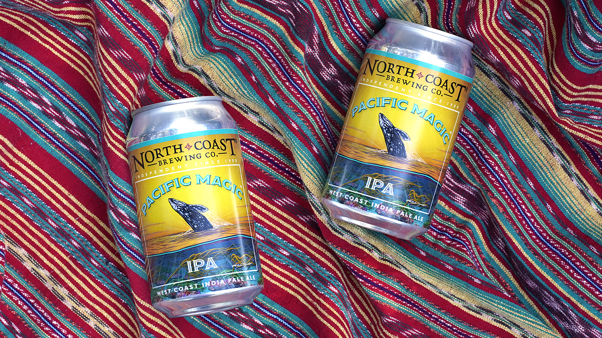 Two cans of Pacific Magic IPA on colorful fabric