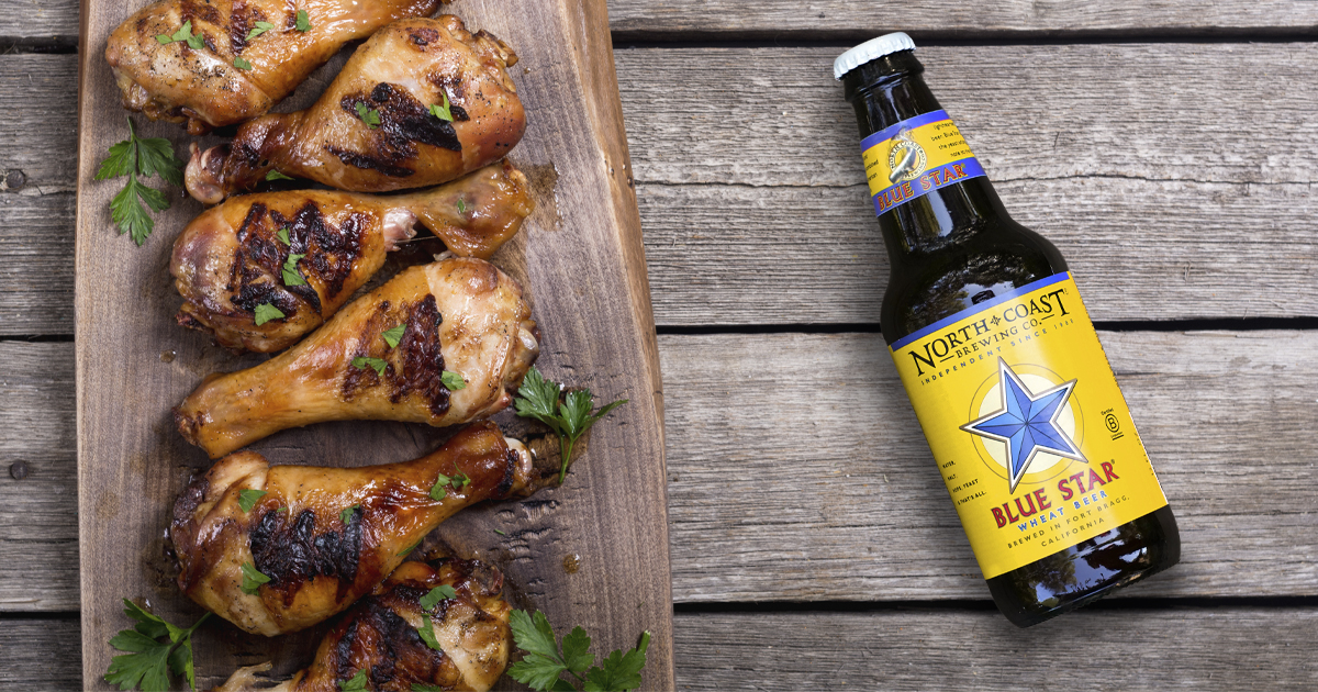 A bottle of Blue Star next to grilled chicken legs
