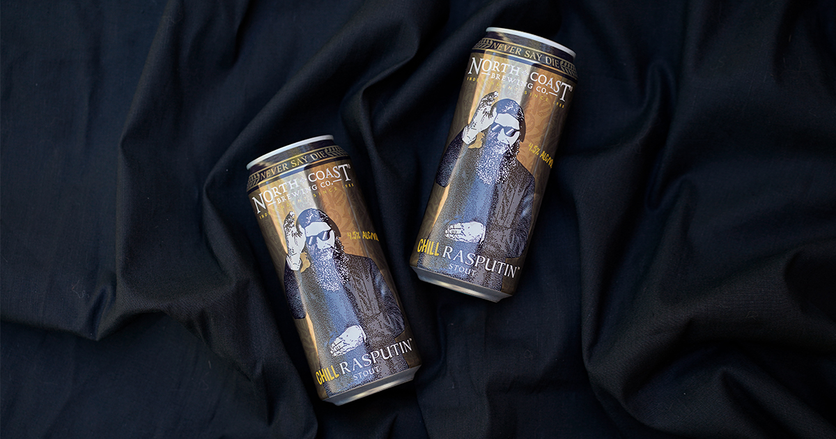Two cans of Chill Rasputin lay on black fabric.